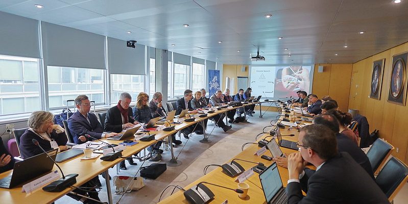 Ein Konferenztisch mit vielen verschiedenen Teilnehmern, die sich gegenübersitzen.