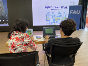 Two students sitting next to each other in front of their laptops, photographed from behind. They develop educational games.