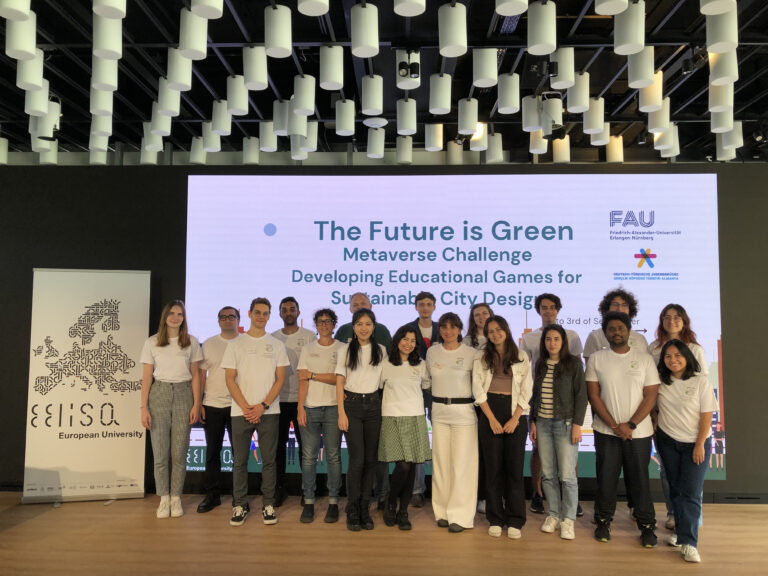 A group of 25 people standing in front of a large screen which reads "The Future is Green", the name of the challenge. A roll-up of the EELISA European University alliance is on the left side next to the group.