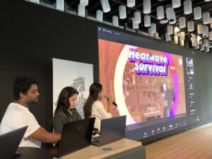 Three students in front of a large screen presenting their educational games. 